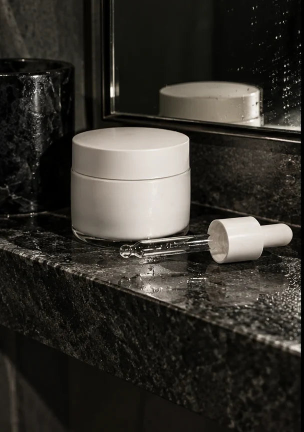 Editorial concept: Minimal skincare bottles on a dark bathroom shelf