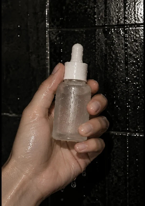 Editorial concept: Serum bottle beside glossy bathroom tiles