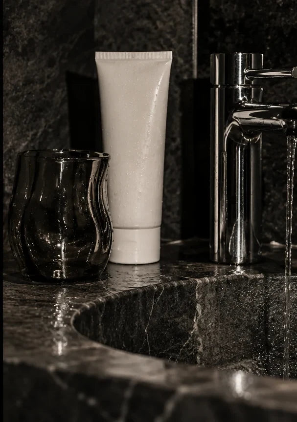 Editorial concept: Skincare beside a chrome bathroom tap